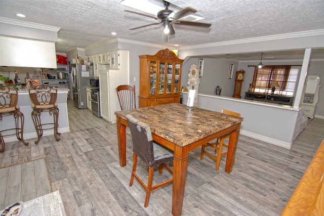 dining room featuring a textured ceiling, light hardwood / wood-style flooring, ceiling fan, and ornamental molding