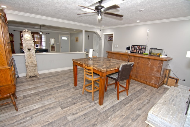 dining space with a textured ceiling, hardwood / wood-style flooring, ceiling fan, and crown molding