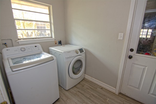 laundry area with washing machine and clothes dryer and light wood-type flooring