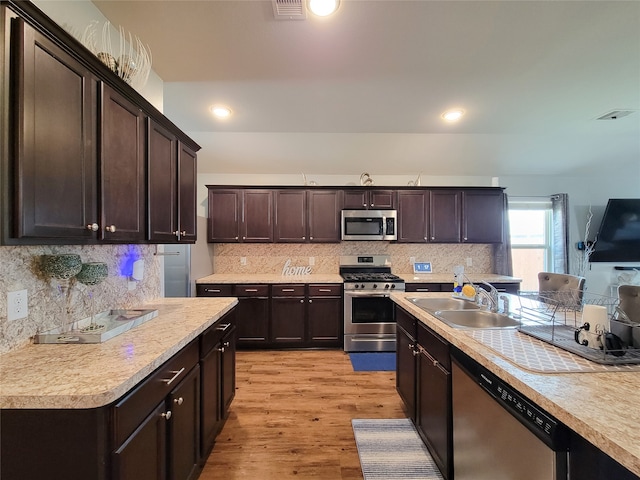 kitchen featuring sink, dark brown cabinetry, stainless steel appliances, and light hardwood / wood-style flooring