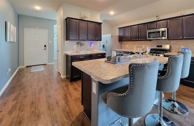 kitchen featuring a kitchen bar, appliances with stainless steel finishes, and a center island with sink