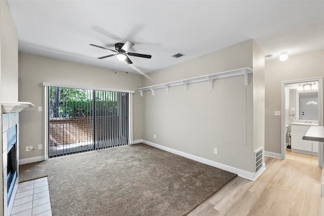 interior space featuring a tile fireplace, ceiling fan, and light hardwood / wood-style flooring