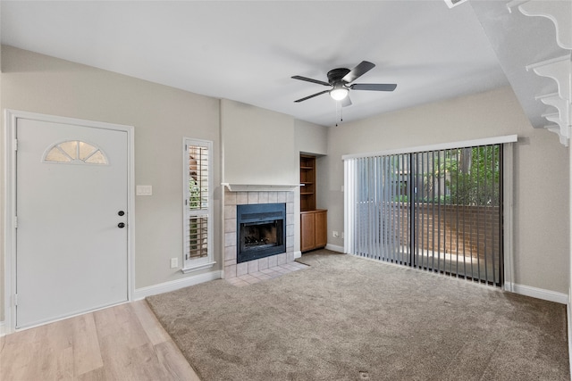 unfurnished living room with ceiling fan, a fireplace, and light hardwood / wood-style floors