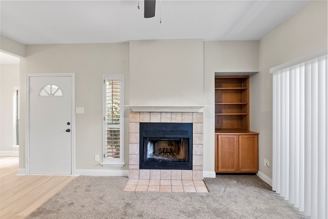 unfurnished living room featuring a tile fireplace and light colored carpet