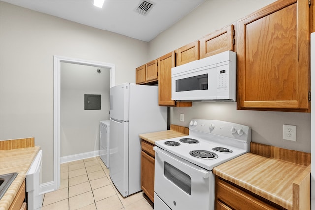 kitchen featuring white appliances, washer / clothes dryer, and light tile patterned flooring