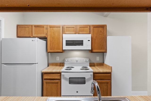 kitchen featuring beamed ceiling, wood-type flooring, white appliances, and sink