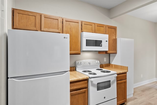 kitchen featuring beam ceiling, white appliances, and light wood-type flooring