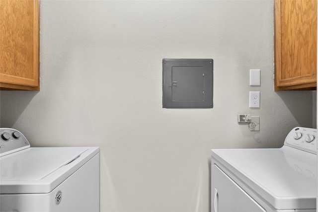 washroom with electric panel, washer and dryer, and cabinets