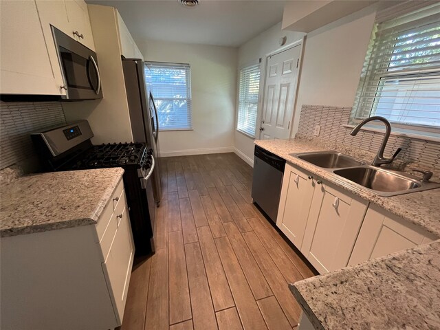 kitchen featuring light wood-type flooring, tasteful backsplash, stainless steel appliances, sink, and white cabinets