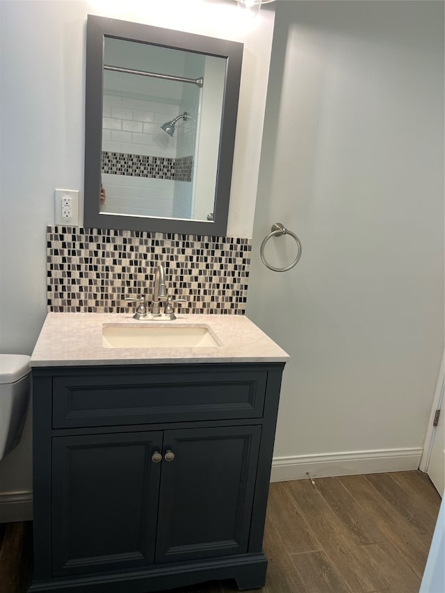 bathroom with decorative backsplash, toilet, wood-type flooring, and vanity