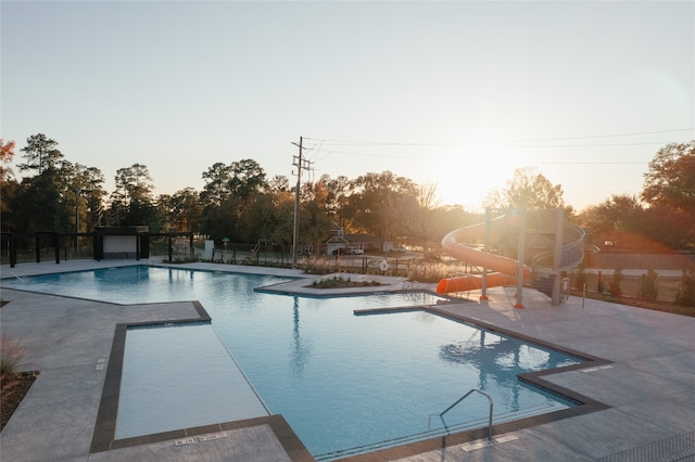 pool at dusk featuring a patio and a water slide