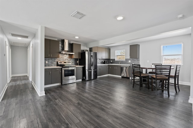 kitchen featuring dark hardwood / wood-style floors, stainless steel appliances, and wall chimney range hood