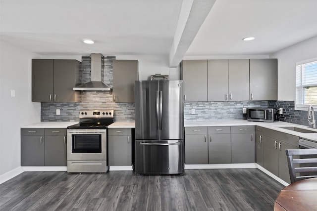 kitchen with gray cabinetry, wall chimney range hood, sink, and appliances with stainless steel finishes