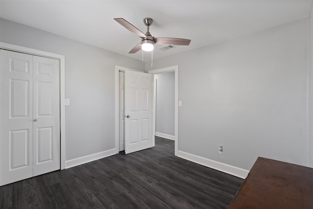 unfurnished bedroom with ceiling fan, dark hardwood / wood-style flooring, and a closet