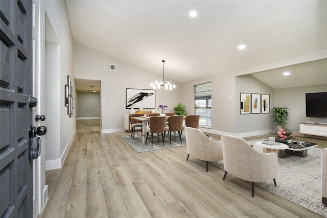 living room with a notable chandelier, light hardwood / wood-style floors, and lofted ceiling