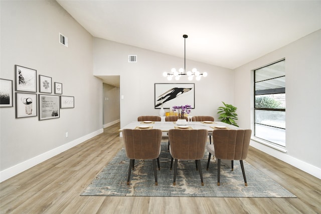 dining area with a notable chandelier, light wood-type flooring, and vaulted ceiling