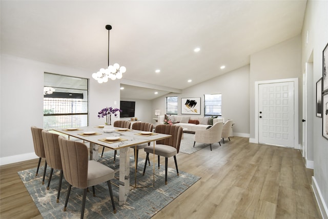 dining space with light hardwood / wood-style floors, lofted ceiling, and an inviting chandelier