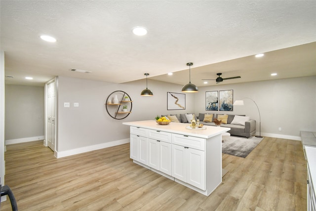 kitchen with ceiling fan, pendant lighting, a center island, light hardwood / wood-style floors, and white cabinetry