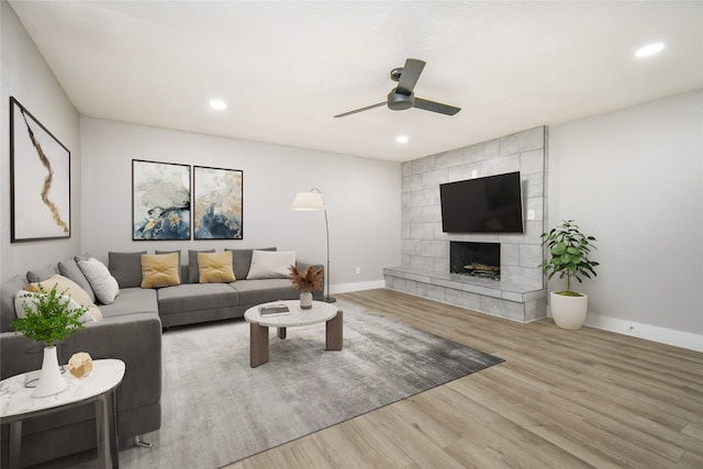 living room featuring ceiling fan, a fireplace, and wood-type flooring