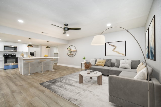 living room with ceiling fan and light hardwood / wood-style floors