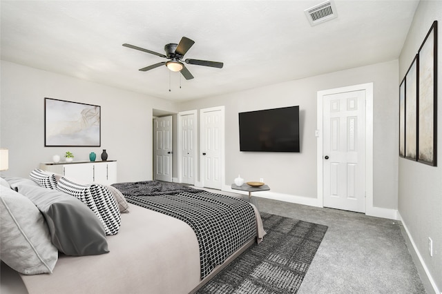 bedroom with carpet flooring, ceiling fan, and two closets