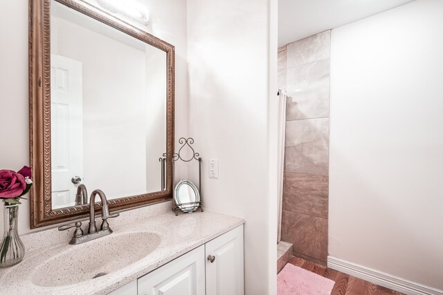 bathroom with hardwood / wood-style flooring, vanity, and a shower