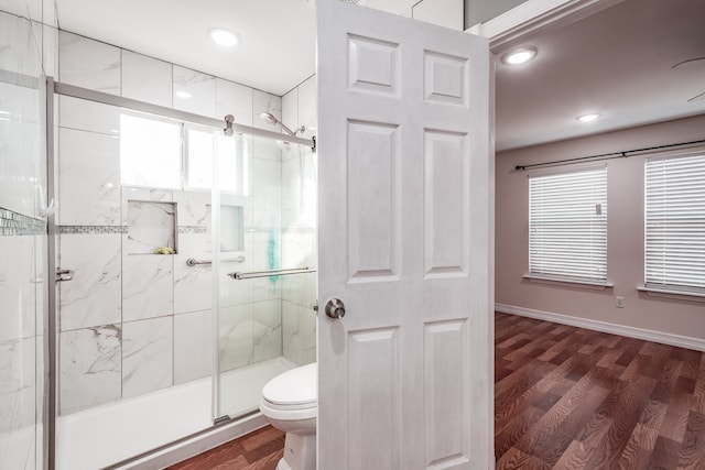 bathroom with toilet, a shower with door, and hardwood / wood-style floors