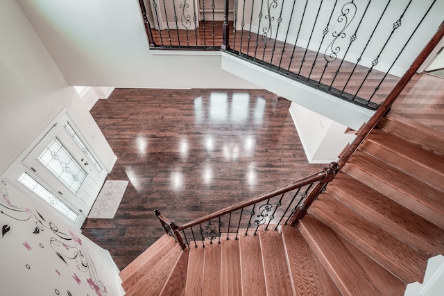 staircase with a towering ceiling and wood-type flooring