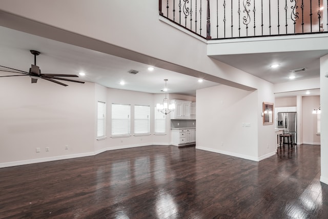 unfurnished living room featuring dark hardwood / wood-style floors and ceiling fan with notable chandelier