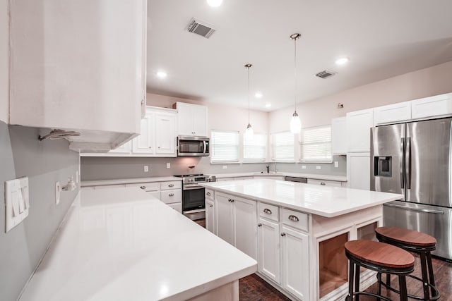 kitchen featuring pendant lighting, appliances with stainless steel finishes, a kitchen island, and white cabinets