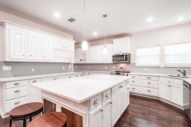 kitchen featuring a kitchen island, white cabinetry, appliances with stainless steel finishes, and pendant lighting