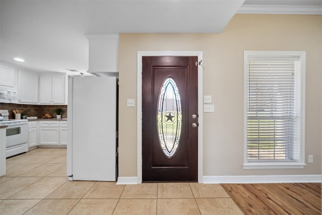 tiled foyer with a wealth of natural light and ornamental molding