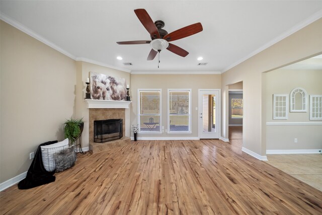 unfurnished living room with light hardwood / wood-style flooring, ceiling fan, ornamental molding, and a tiled fireplace