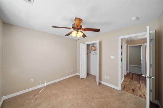 unfurnished bedroom featuring ceiling fan, a closet, and light colored carpet