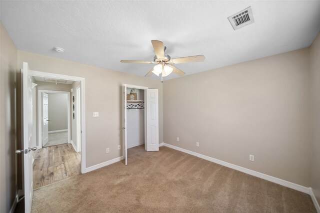 unfurnished bedroom featuring a closet, light colored carpet, and ceiling fan