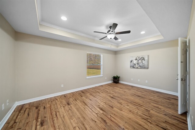 unfurnished room with wood-type flooring, a raised ceiling, and ornamental molding