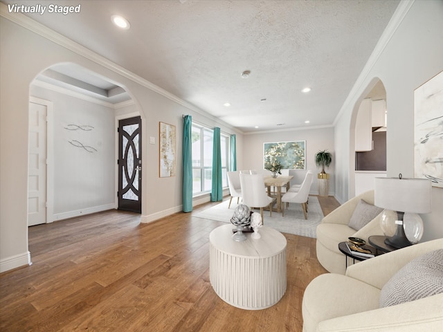 living room with a textured ceiling, light hardwood / wood-style floors, and ornamental molding