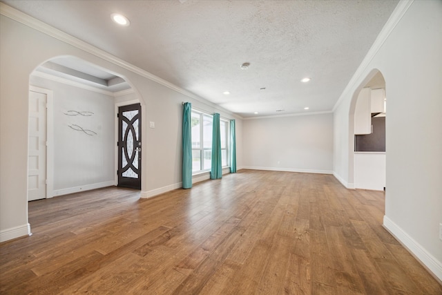 empty room with light hardwood / wood-style floors, a textured ceiling, and ornamental molding