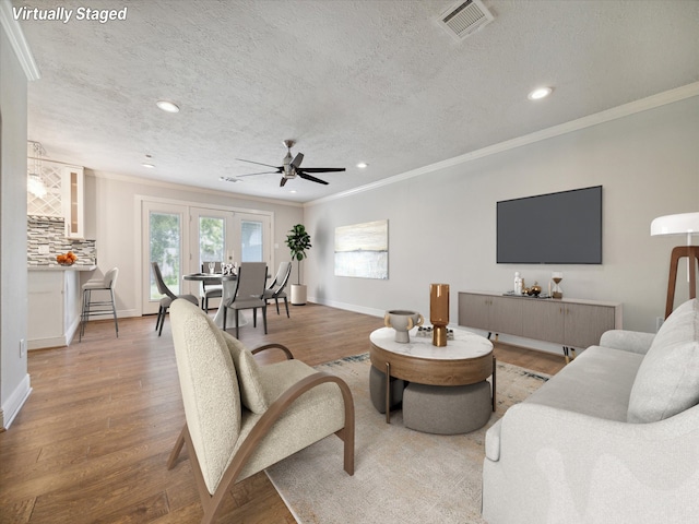 living room with hardwood / wood-style floors, a textured ceiling, and ornamental molding