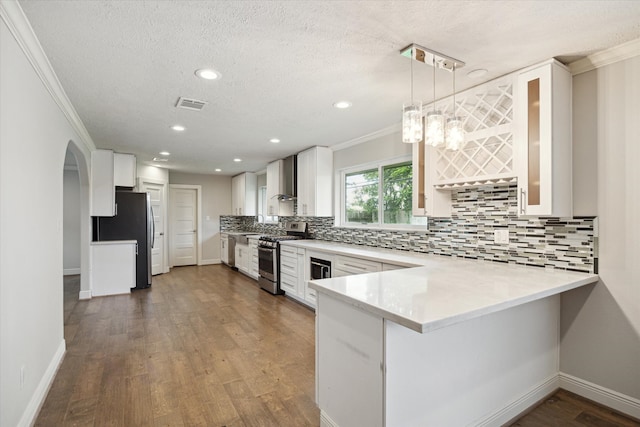 kitchen with dark hardwood / wood-style floors, kitchen peninsula, decorative light fixtures, white cabinets, and appliances with stainless steel finishes