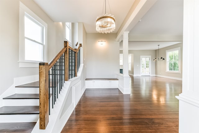 foyer entrance featuring decorative columns, dark hardwood / wood-style flooring, and a notable chandelier