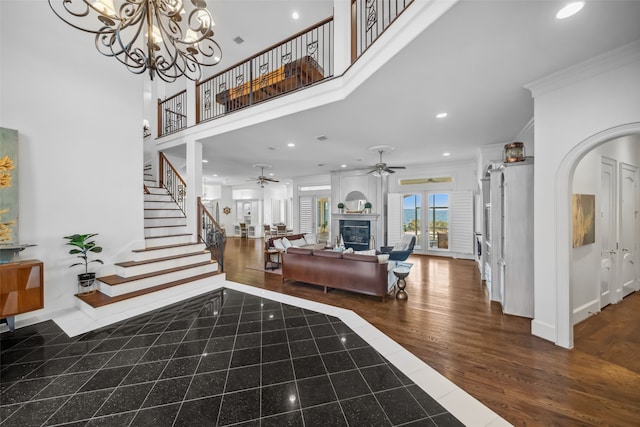 foyer entrance featuring a large fireplace, ornamental molding, dark wood-type flooring, and a chandelier