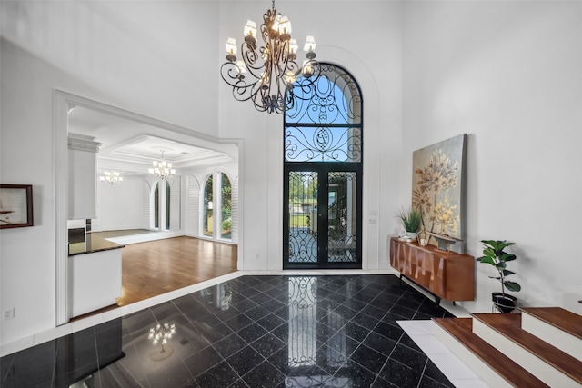 foyer with dark hardwood / wood-style flooring, a towering ceiling, and a chandelier