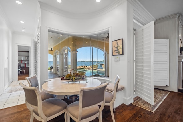 dining room featuring crown molding, a water view, and dark hardwood / wood-style floors