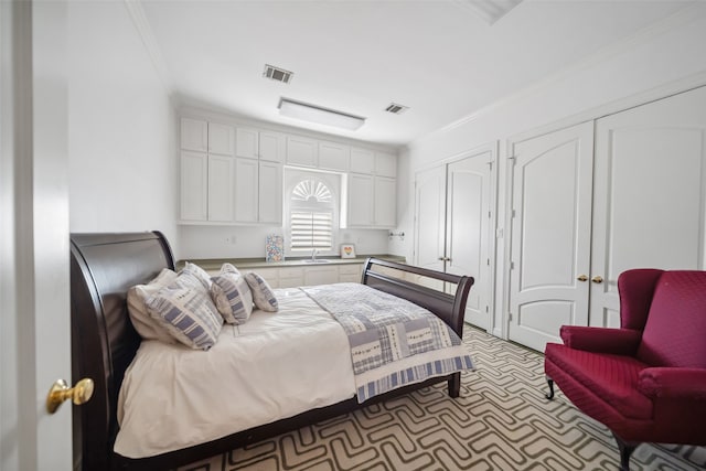 bedroom featuring sink, crown molding, and two closets