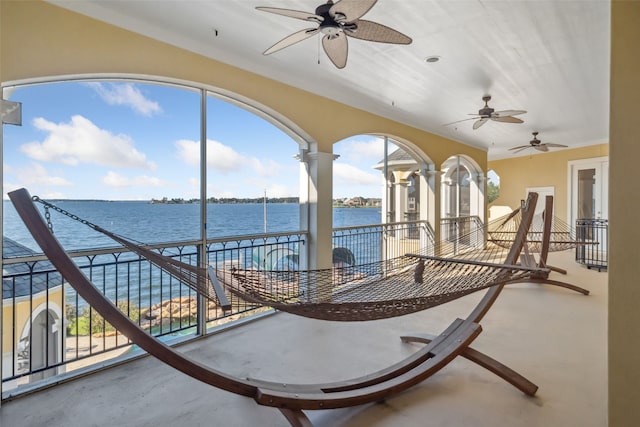 view of patio featuring ceiling fan, a balcony, and a water view