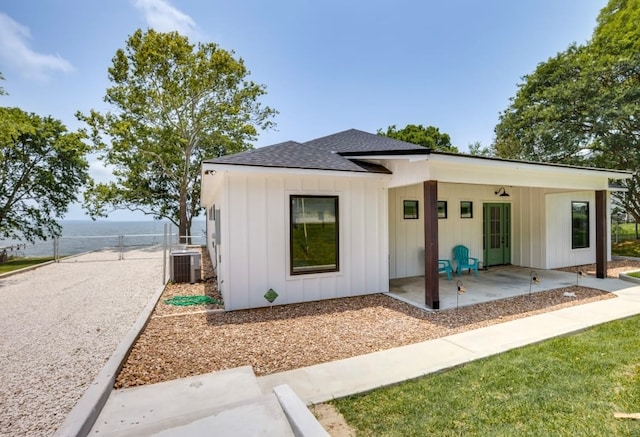 back of property with central air condition unit, a water view, and a patio