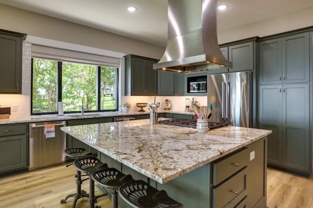 kitchen with sink, light hardwood / wood-style flooring, a kitchen island, island exhaust hood, and stainless steel appliances