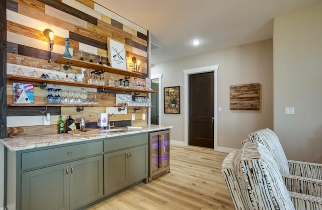 bar featuring green cabinets, sink, beverage cooler, and light hardwood / wood-style flooring