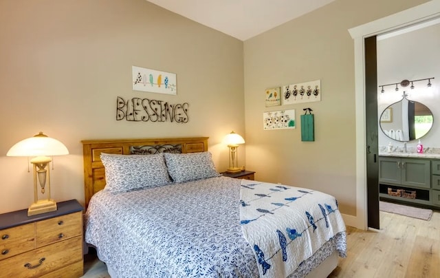 bedroom featuring light wood-type flooring, ensuite bath, and sink